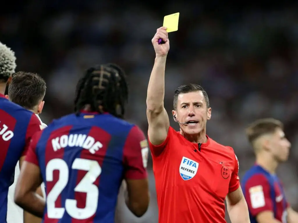  Lucas Vázquez a football referee, holding up a yellow card to a player in protest