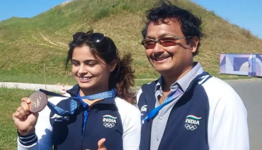 A close-up of Manu Bhaker holding her bronze Olympic medal, its intricate details gleaming against a backdrop of the Indian flag, symbolizing her national pride.